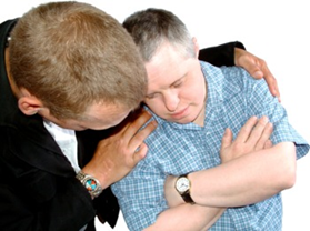 A man looking sad with his friend's arms around his shoulders
