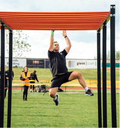 A man hanging from monkey bars completing an obstacle course