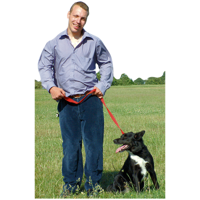 A man with a black and white dog standing on the grass