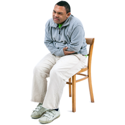 A man sitting on a chair with both arms wrapped around his stomach as if in pain