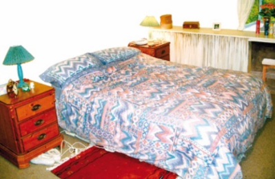 A bedroom with a double bed, bedside cabinets and a dressing table