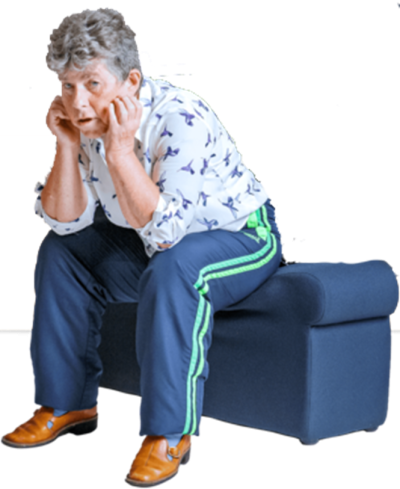 A woman sitting on a blue bench leaning forward with her elbows on her knees looking fed up